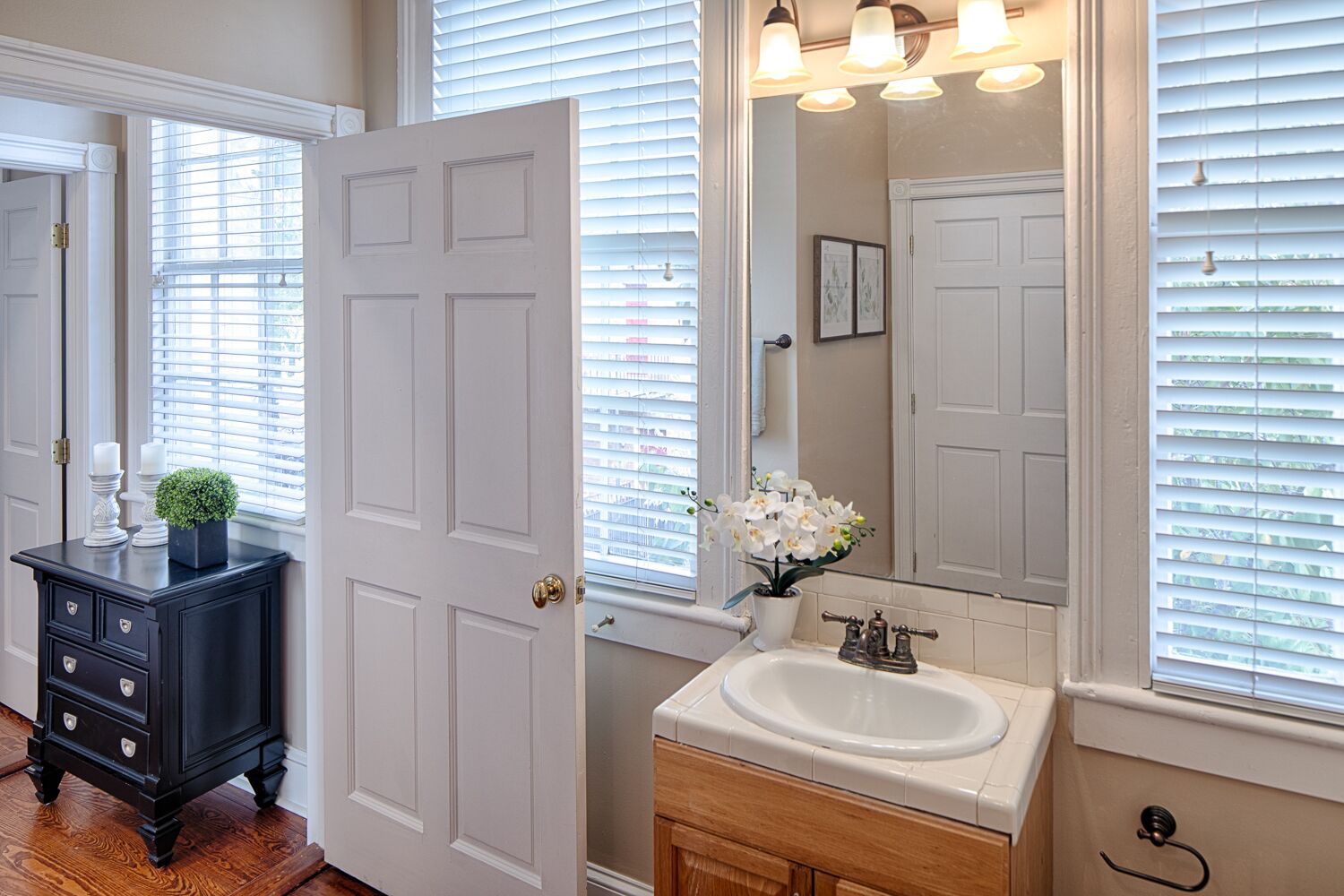 A bathroom with a white sink, a dark wooden vanity, and a large mirror.