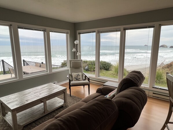 A living room with a view of the ocean, a sofa, a table, and a chair. - On the Beach. Yes, on the Beach. It's all about the View and being on the Beach (Arch Cape)