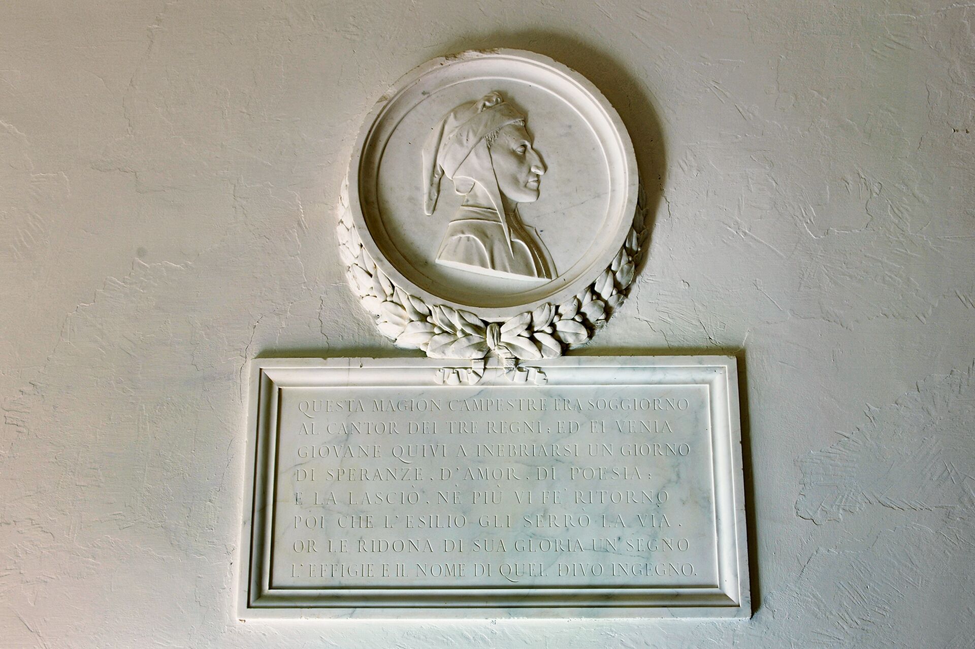 Une plaque de marbre portant un portrait gravé et un texte.