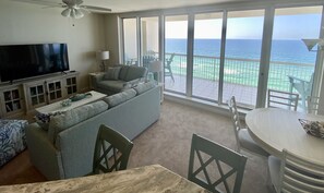 Relax in style with a spacious living area featuring a sofa, flat-screen TV, and dining table, plus a balcony with ocean views.