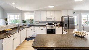 Une cuisine moderne avec des meubles blancs, des appareils en acier inoxydable et un plan de travail en granit.