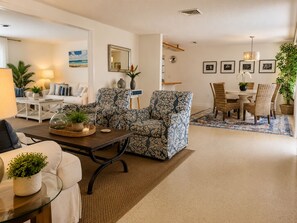 A modern living room with a sofa, armchairs, a coffee table, and a dining area with a table and chairs. - Relaxing 3BR/2Ba Oasis with Heated Pool. (Sarasota)