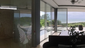 Una habitación moderna con grandes puertas de cristal que dan a un balcón con vistas al mar.