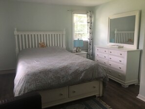 A bedroom with a bed, dresser, and a mirror.