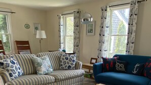 A living room with a striped sofa, a blue sofa, a wooden coffee table, and a blue patterned rug. - Beautiful 2 Bedroom Cottage Just Short Stroll To Town Neck Beach (Sandwich)