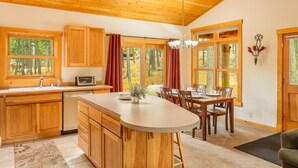 A spacious kitchen with wooden cabinets, a large island, and a dining area with a table and chairs.