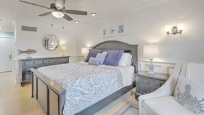 A bedroom with a bed, nightstands, a ceiling fan, wall art, and a decorative pillow.