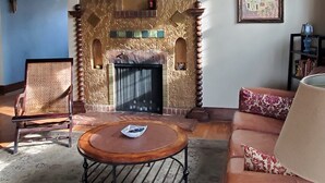 Una sala de estar con chimenea, candelabro, un cuadro enmarcado y un sofá.
