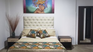 A bedroom with a tufted headboard, floral-patterned bedding, and a painting above the bed. - Hotel San Blass (La Unión)