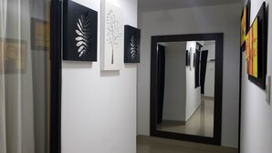 A hallway with modern art on the walls, a large mirror, and a door leading to another room. - Hotel San Blass (La Unión)