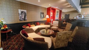 A hotel lobby with a curved sofa, armchairs, a coffee table, and a bar area. - Gateway  Motor Inn (Masterton)
