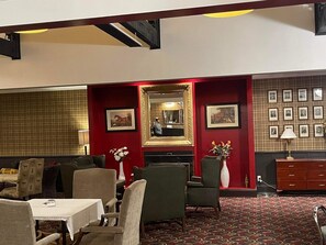 A room with a red accent wall, a fireplace, framed pictures, and a mirror.