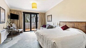 A hotel room with a large bed, a desk with a chair, a television, and a sliding glass door to the outside. - Gateway  Motor Inn (Masterton)