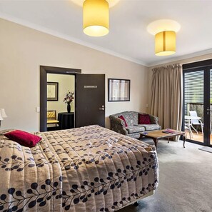 Une chambre d’hôtel comprenant un lit, un canapé, une petite table et une porte donnant sur un balcon.