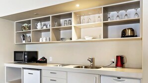 A modern kitchen with white cabinetry, a built-in microwave, a dishwasher, and a sink. - Gateway  Motor Inn (Masterton)