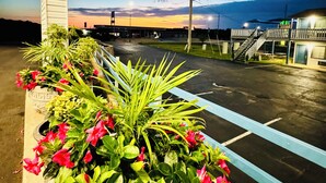 A parking lot with a flower bed and a building in the background.