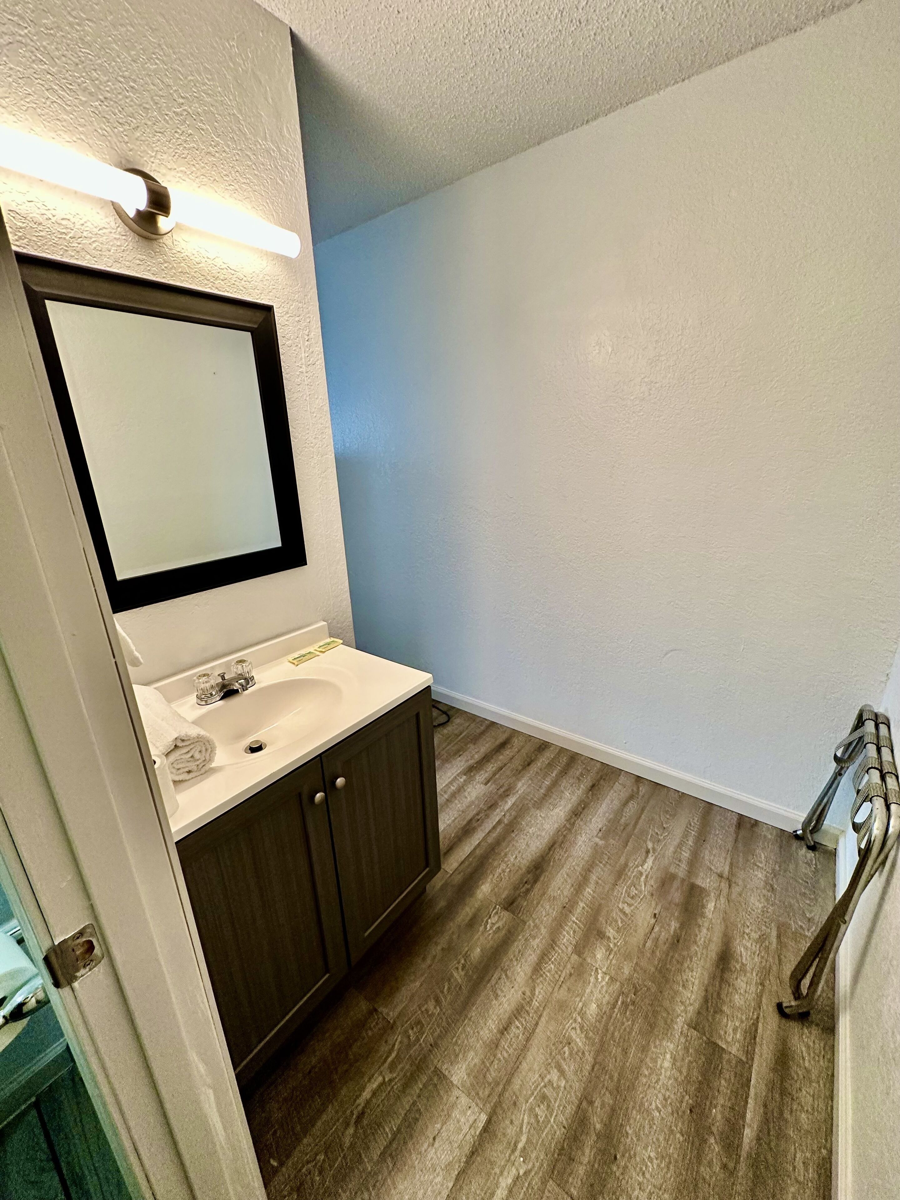 A bathroom with a white sink, dark wooden cabinets, a mirror, and a light blue wall.