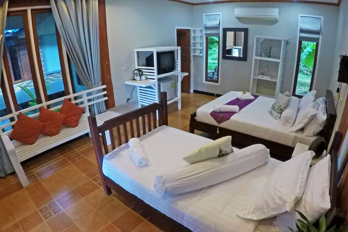 Ein Hotelzimmer mit zwei Betten, einem Fernseher und einer kleinen Sitzecke mit Kissen.