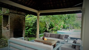 A covered outdoor seating area with a brick fireplace, a sofa, and a coffee table. - Villa Kendi (Glenmore)