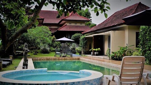 A swimming pool with a tiled edge, a lounge chair, and a statue in a garden area. - Villa Kendi (Glenmore)