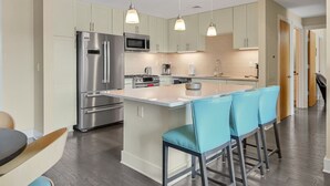 A modern kitchen with a central island, stainless steel appliances, and light-colored cabinetry. - Balcony Condo in Downtown Asheville (Asheville)