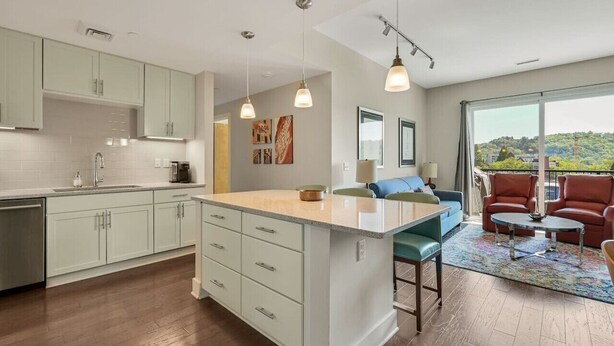 A modern kitchen with a central island, light-colored cabinets, and pendant lighting. - Balcony Condo in Downtown Asheville (Asheville)