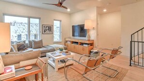 A modern living room with a sofa, coffee table, and a TV stand. - 243 Short Coxe Ave Townhome (Asheville)