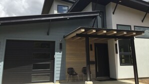 A modern two-story house with a garage, a covered porch, and a large window.