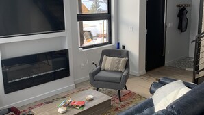 A modern living room with a grey sofa, a coffee table, and a TV mounted on the wall.