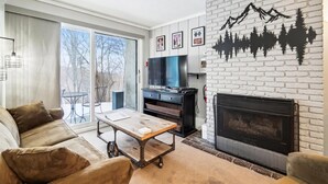 Una sala de estar con chimenea, un sofá, una mesa de centro y un televisor.