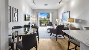 A modern living room with a dining area, large windows, and a view of the outdoors. - Roomy and Accessible Downtown Balcony Condo (Asheville)