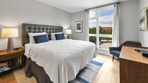 A modern hotel room with a large bed, a desk, and a view of the outdoors. - Roomy and Accessible Downtown Balcony Condo (Asheville)