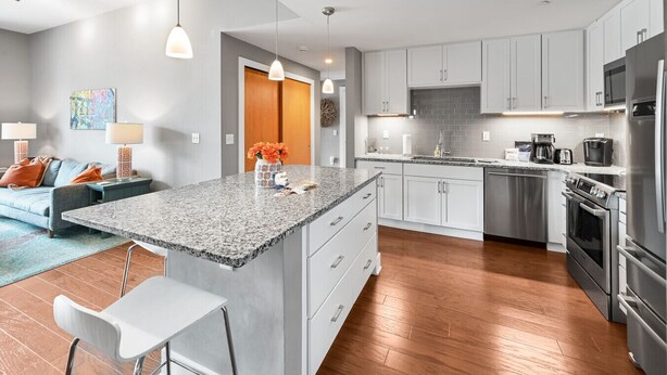 Una cocina moderna con encimeras de granito, electrodomésticos de acero inoxidable y armarios blancos.