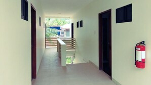 A corridor with a staircase leading to an outdoor area, a fire extinguisher mounted on the wall, and a door on the right. - Dolphin Bay Resort Puerto Galera (Puerto Galera)