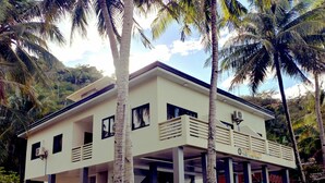 A two-story building with a balcony, surrounded by palm trees. - Dolphin Bay Resort Puerto Galera (Puerto Galera)