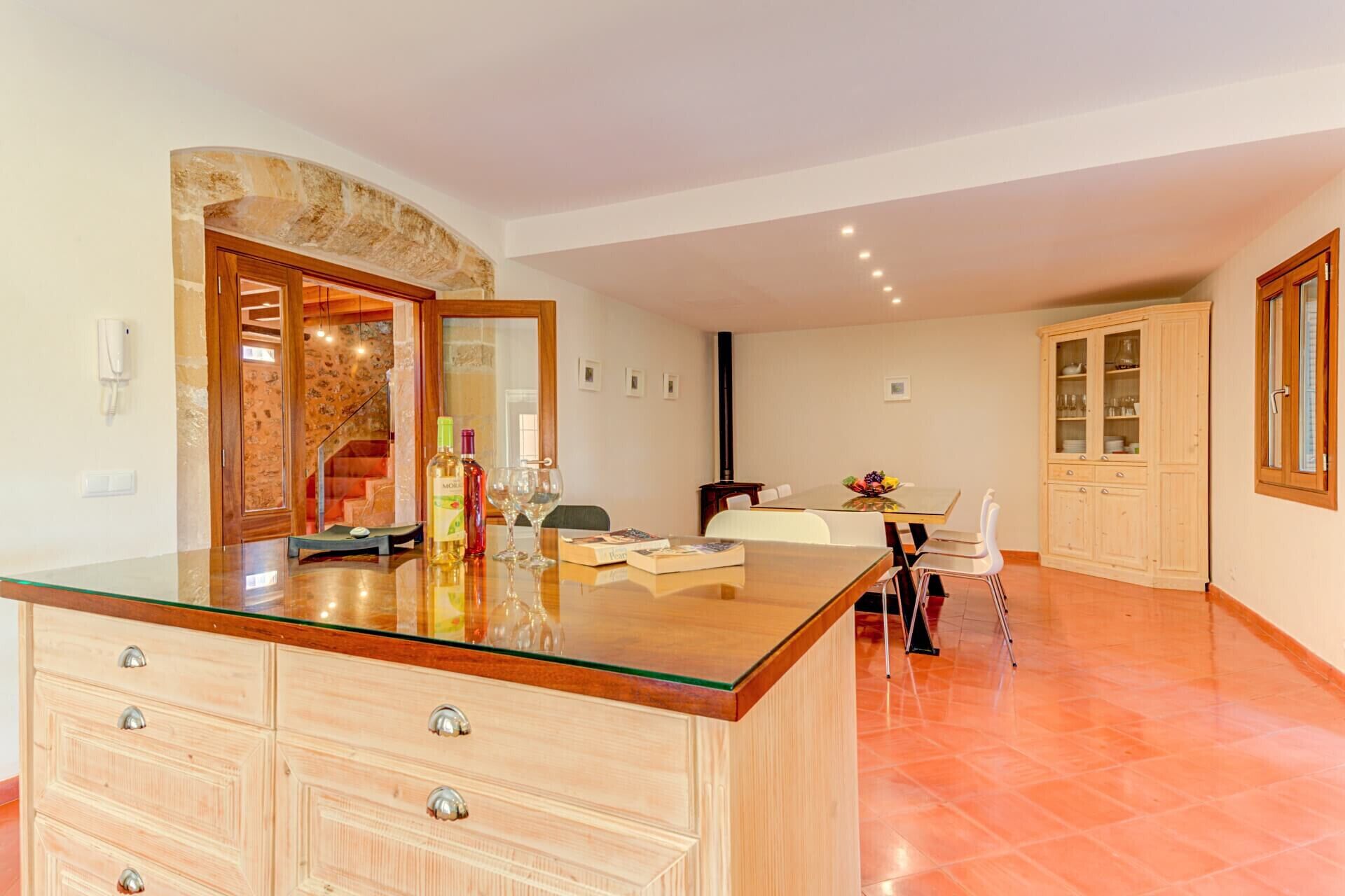 A spacious kitchen with a central island, a dining area with a table and chairs, and a kitchen cabinet with glass doors.