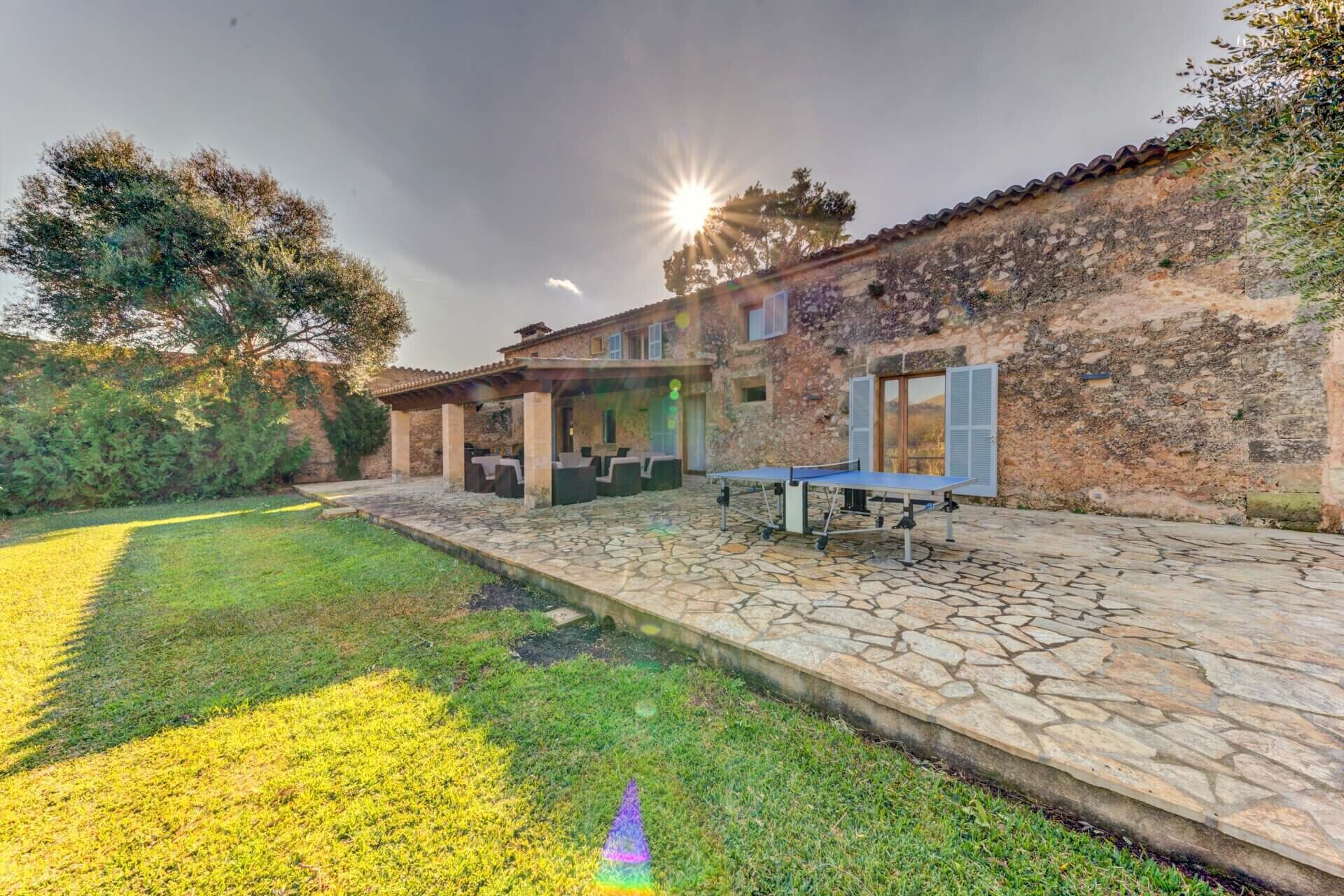 A stone-floored patio with outdoor seating and a ping pong table.