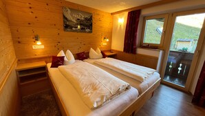 Una habitación con paneles de madera, una cama, dos mesitas de noche, luces fijadas a la pared y un ventanal con vistas.