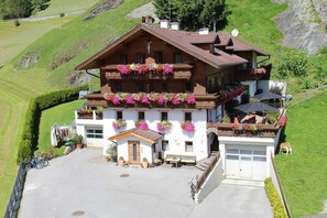 Una cabaña con balcones decorados con flores, un garaje y un pequeño espacio al aire libre para sentarse.