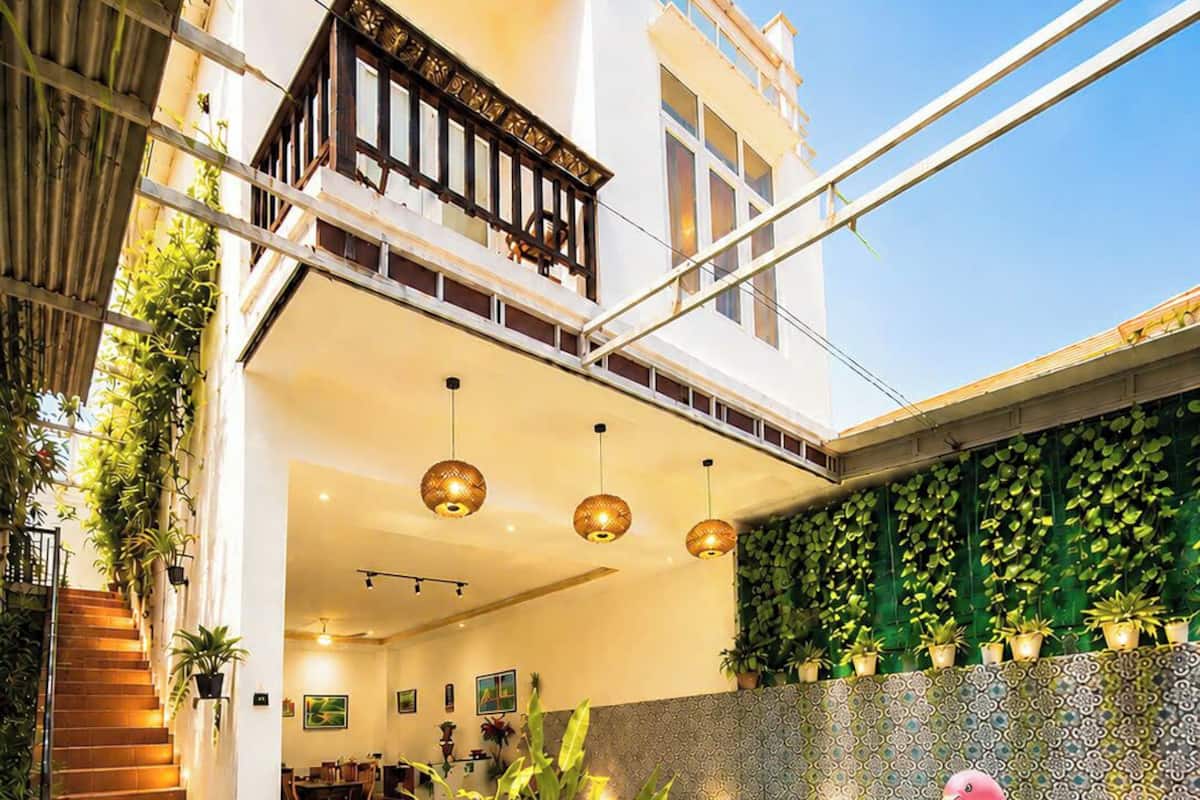 Zona de piscina con un flotador de flamenco rosa, plantas en macetas y una escalera que lleva a un balcón.