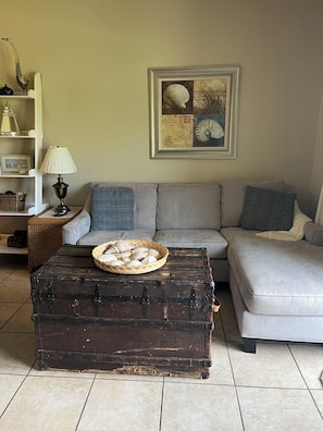 A living room with a grey sofa, a wicker basket with seashells, a lamp, and a framed artwork on the wall. - Direct Gulf View,  Designer Decor! Steps to sand. Sleeps 6. (Destin)