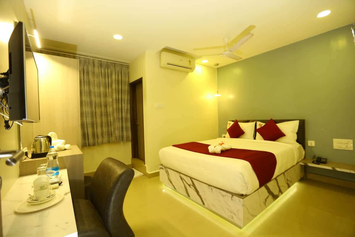 A hotel room with a bed, a desk, a chair, an air conditioner, and a ceiling fan.
