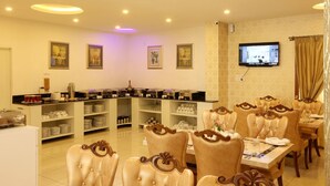 A hotel dining area with a buffet, dining tables, and chairs. - High Sky Krishna Global Villaments (Bengaluru)