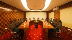 A conference room with a long table, chairs, a red carpet, and a projector screen. - High Sky Krishna Global Villaments (Bengaluru)