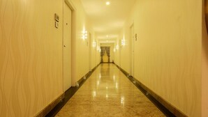 A long, well-lit hallway with doors on both sides and a marble floor. - High Sky Krishna Global Villaments (Bengaluru)