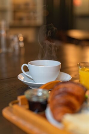 A breakfast tray with a cup of coffee, a glass of orange juice, and a croissant.