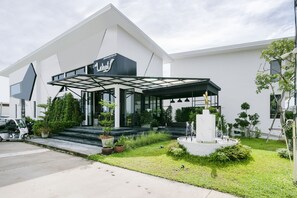 A modern building with a covered entrance, steps leading up to the entrance, and a small garden area with plants and a fountain. - CAPITAL O1009 Leleaf Valley Pool Villa Resort Hua Hin (Hua Hin)