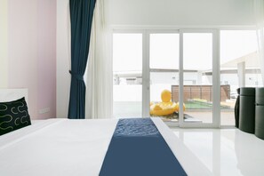 A hotel room with a bed, a window with a view of a pool and outdoor area, and a chair. - CAPITAL O1009 Leleaf Valley Pool Villa Resort Hua Hin (Hua Hin)