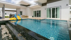 Piscina interna moderna com escorregador, portas de vidro transparente e área de terraço.