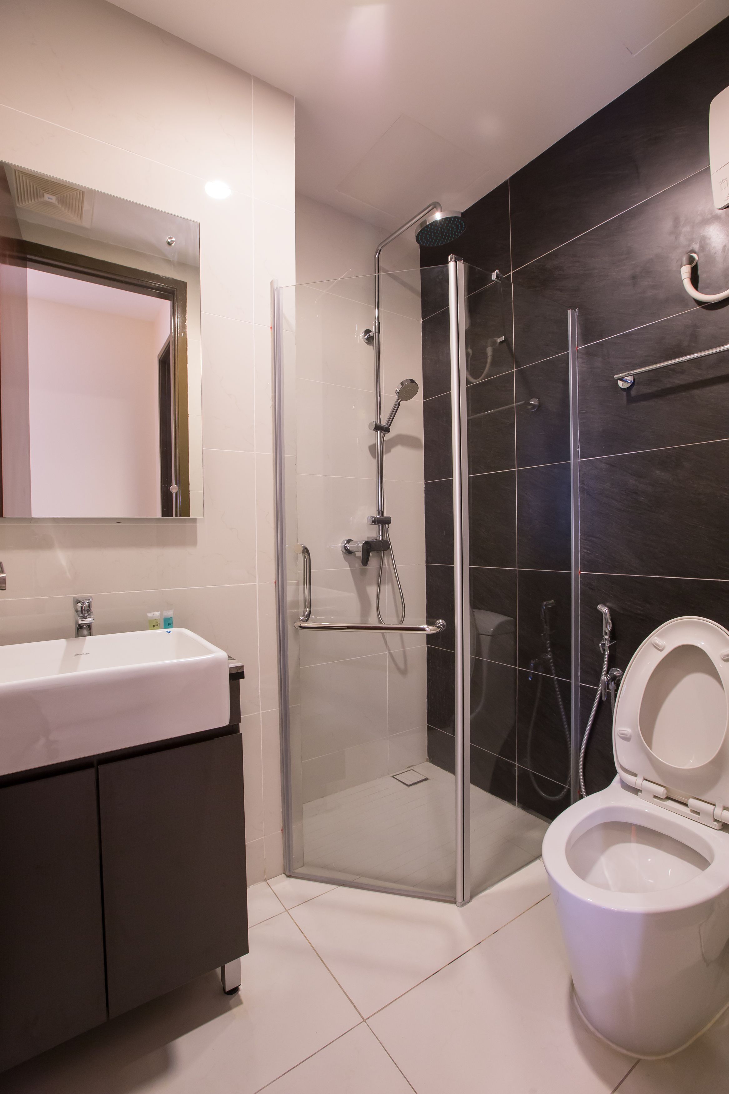 A modern bathroom with a glass-enclosed shower, a white sink with a mirror above it, and a toilet.